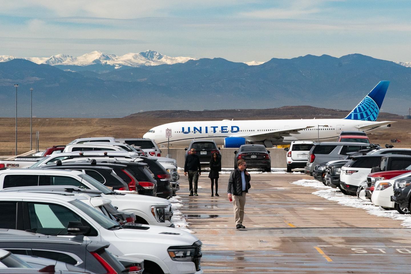A United Airlines jet taxis in the background as people make their way across the top deck of the West Garage