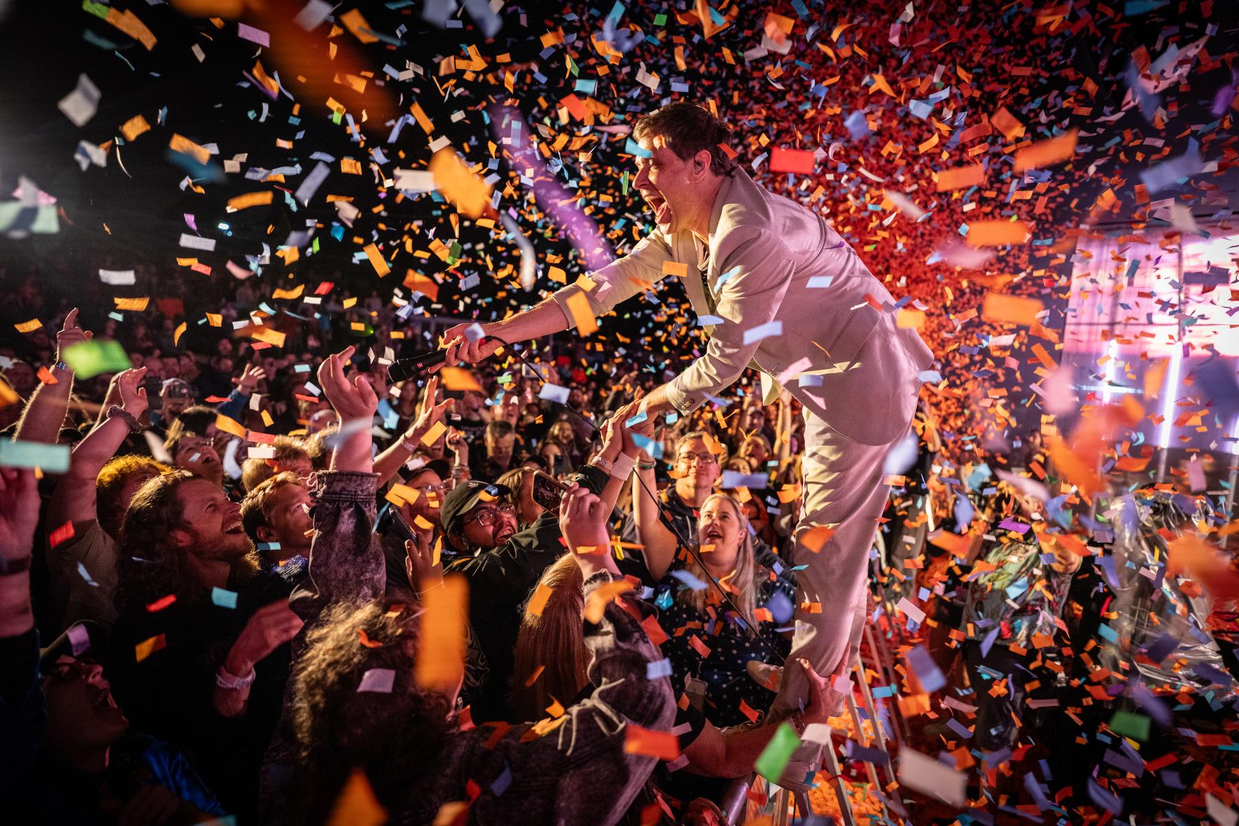 OK Go’s Damian Kulash stands atop the stage barricade and greets fans in a blizzard of confetti at Indieverse