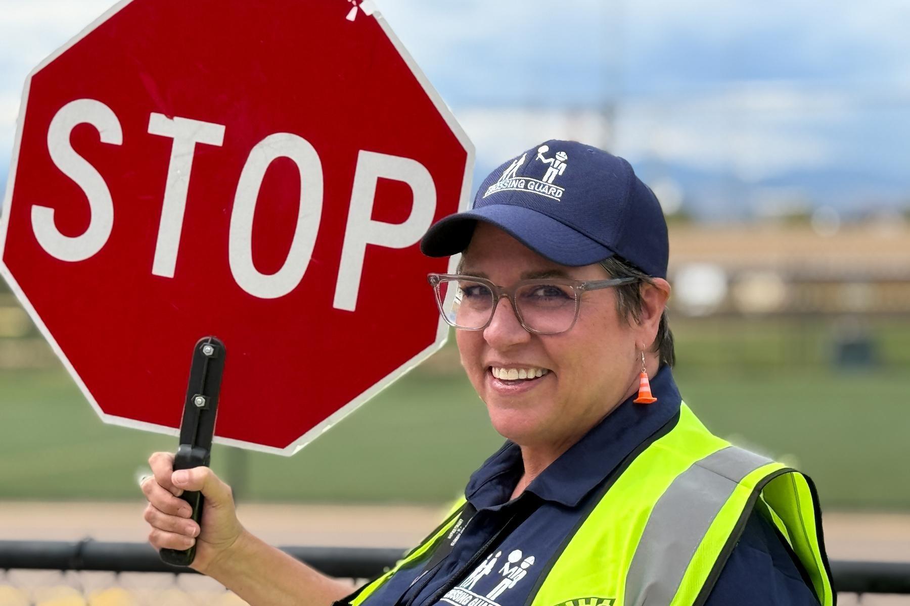 Woman in green vest holds a stop sign