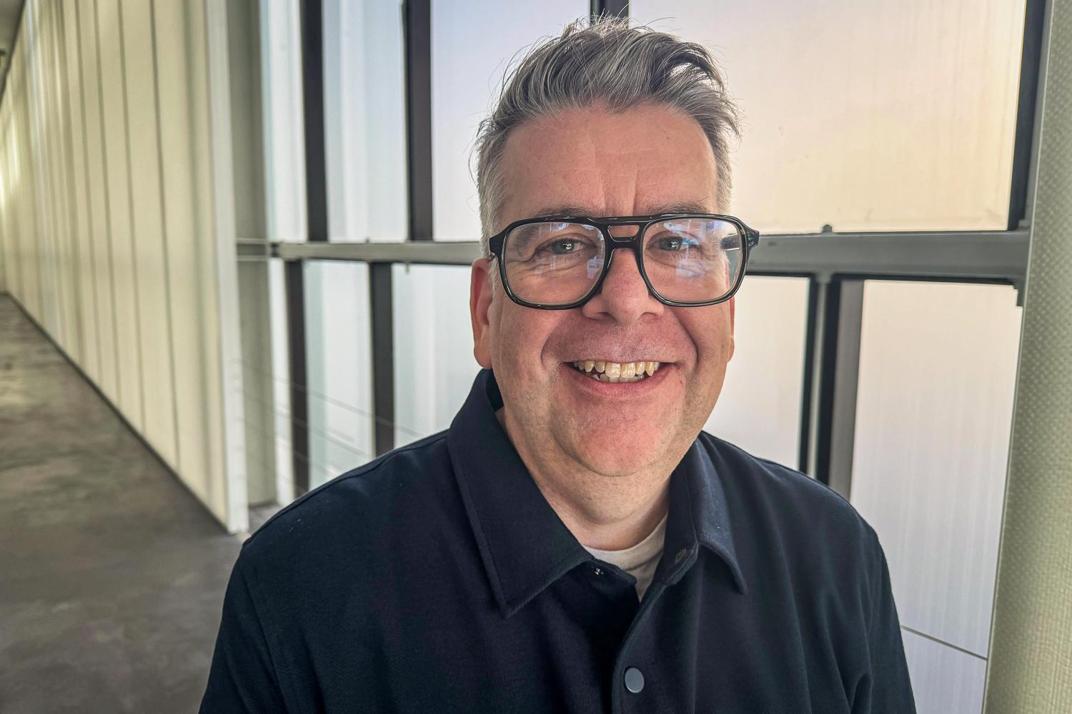 A man wearing glasses and a button-up shirt is smiling for the camera.