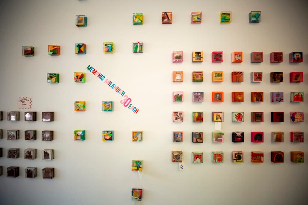 The image features a wall with a variety of small, colorful, and unique pictures. These pictures are arranged in a visually appealing manner, creating an interesting and engaging display. The wall serves as a backdrop for the artwork, which is likely intended to be appreciated by viewers.