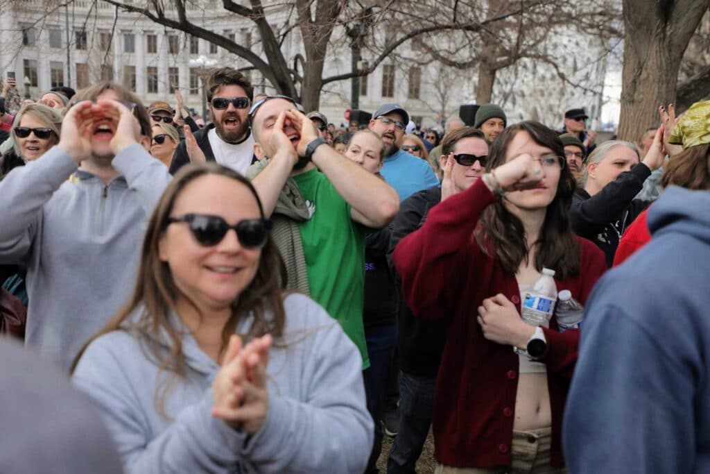 A group of people clap and cheer.