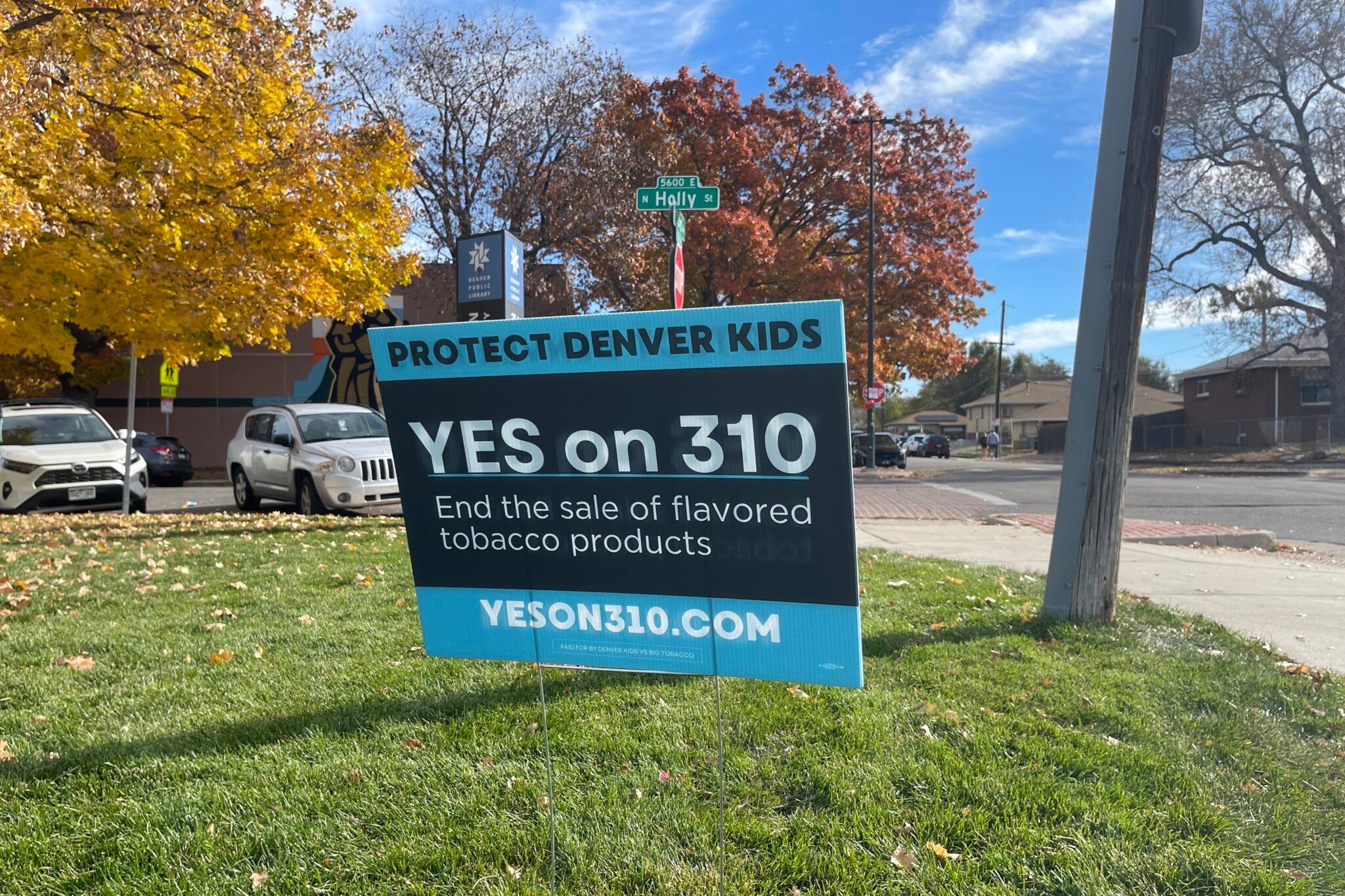 A "Yes on 310" sign is posted in a grassy area, with parked cars and tress with fall leaves.